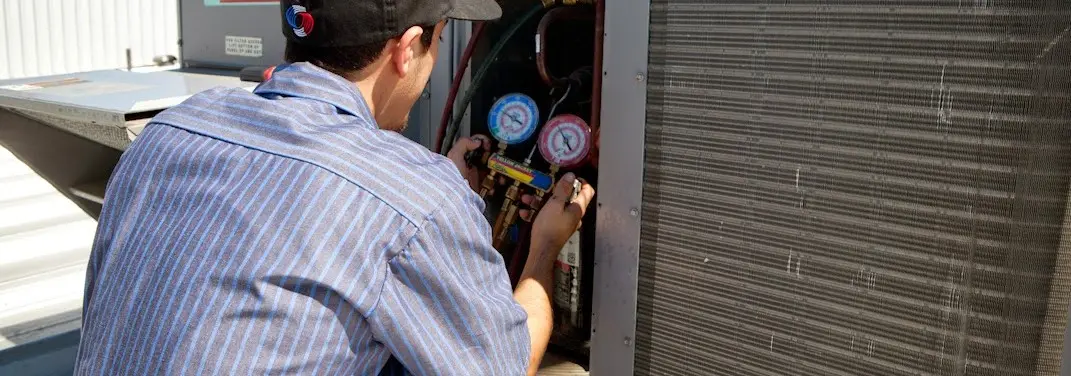 HVAC technician servicing a condenser unit in Stowe